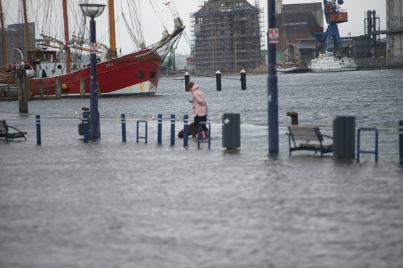 Flensburg, Schleswig-Holstein, Hochwasser in Flensburg am Hafen West, Flaniermeile Schiffbr�cke, Wasser der Ostsee tritt �ber die Kaikante, Person waten durch das Wasser. Aufnahme vom 19.10.2023. ***  ...