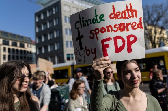 BERLIN, GERMANY - APRIL 21: Fridays for Future climate activists protest outside the Transport Ministry with a note &quot;Climate death sponsored by FDP&quot; before marching to the venue where the pr ...