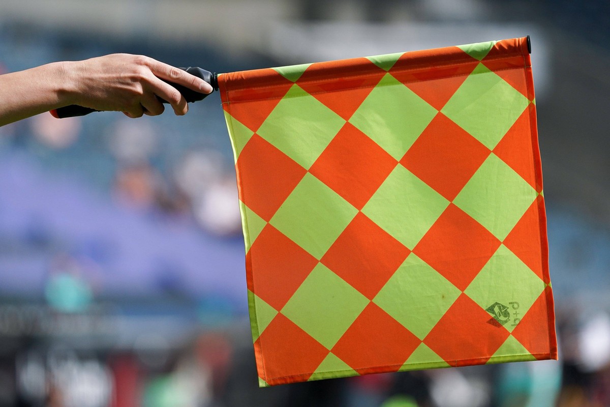 Die Linienrichterin zeigt eine Abseitsstellung an, rot-gelb karierte Flagge, Abseits, Abseitsposition, Schiedsrichterassistent, Linienrichter, Schiedsrichter, Schiedsrichterwesen, Regeln, Fu
