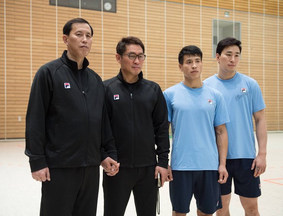 Trainer Myong Chol Sin, Cheftrainer Young Shin Cho, der suedkoreanische Spieler und Kapitaen Suyoung Jung, sowie der nordkoreanische Spieler Song Jin Ri (von links) posieren für ein Foto. Sin und Shin Cho halten dabei gemeinsam die Hand.