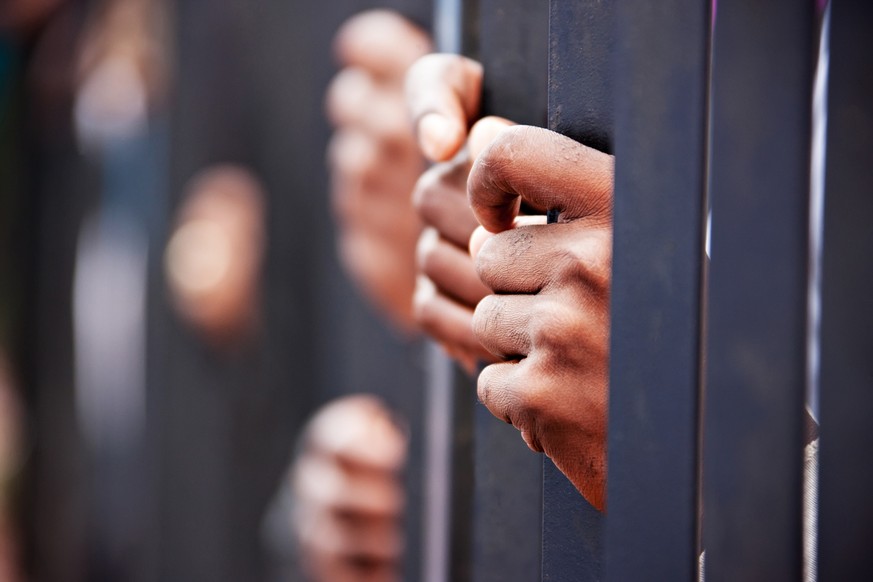 Stolen life, group of hands African people behind bars holding them.