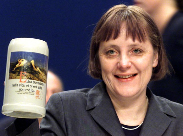 FILE PHOTO: Newly elected Christian Democratic (CDU) party leader Angela Merkel holds a traditional Bavarian one litre beer mug a gift from CSU leader Edmund Stoiber at a CDU party convention in Essen ...