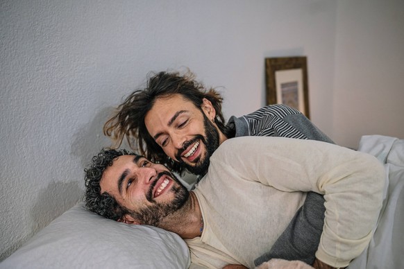 Happy gay couple cuddling in bed at home model released, Symbolfoto property released, GDBF00042