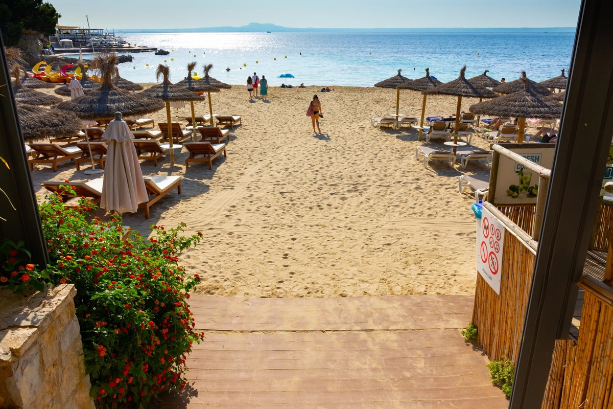 Ses Illetes, Majorca, Balearic islands, Spain. July 20th, 2022 - Access to the beach with umbrellas and loungers of the Balneario Illetas spa beach club