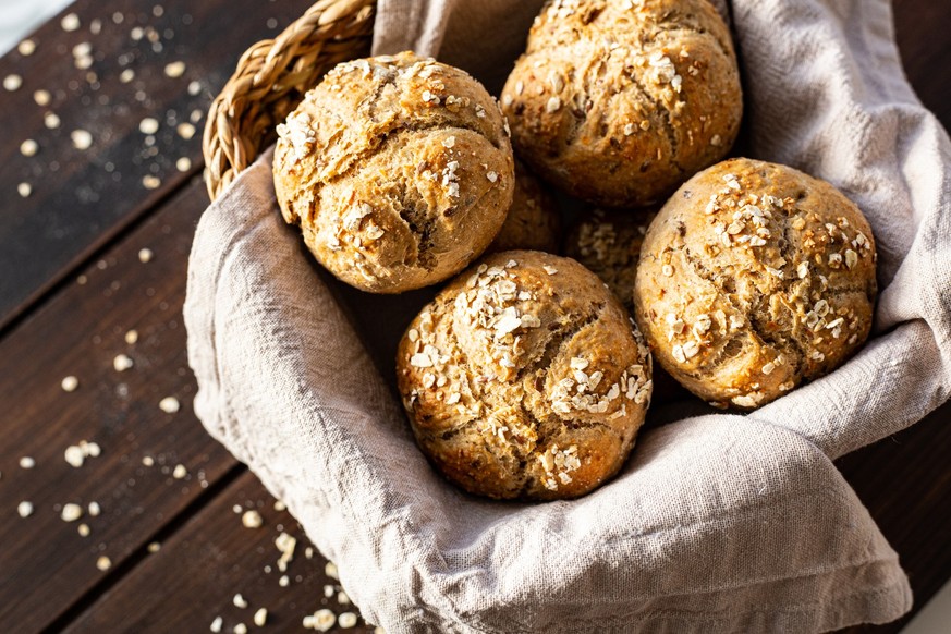 Breakfast rolls in a bread basket on wooden plank. Part of a series.