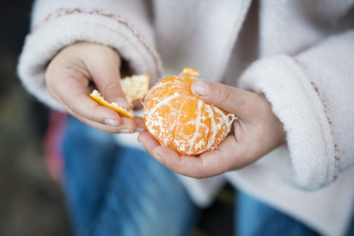 Little girl peeling orange peel
