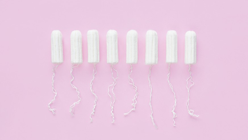 Menstrual period concept. Woman hygiene protection. Cotton tampons on pink background. Top view, flat lay.