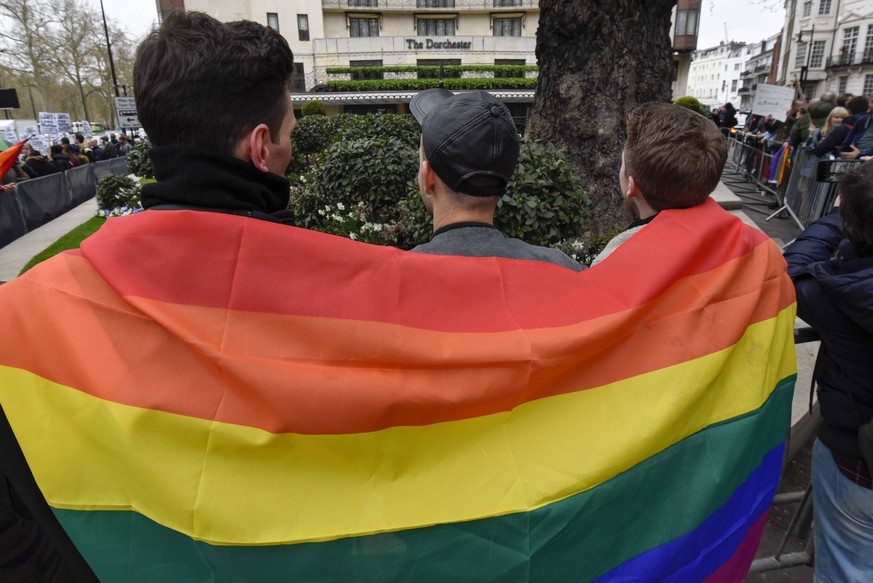 April 6, 2019 - London, UK - LONDON, UK. Members of the LGBT community wear a rainbow flag during a protest outside the Brunei-owned Dorchester Hotel in reaction to reports that the Sultan of Brunei d ...