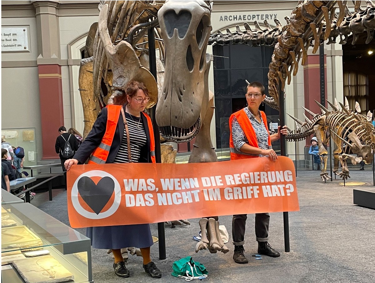 Zwei Klimaaktivistinnen mit einem Banner "Was, wenn die Regierung das nicht im Griff hat?" haben sich im Berliner Museum für Naturkunde an den Haltestangen eines Dinosauriers festgeklebt. Di ...