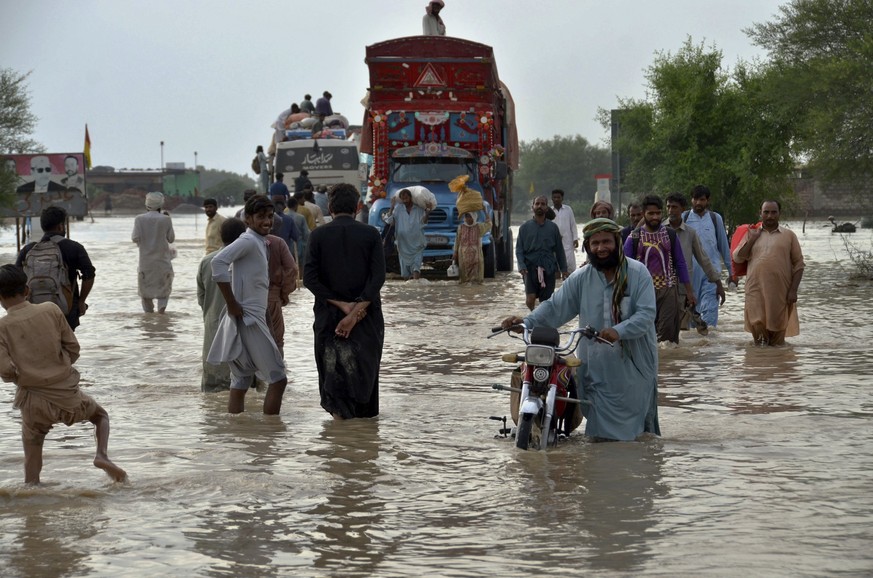 FILE - People navigate through a flooded road caused by heavy monsoon rains, in Nasirabad, a district of Pakistan's southwestern Baluchistan province, Aug. 22, 2022. A new study says human-caused clim ...
