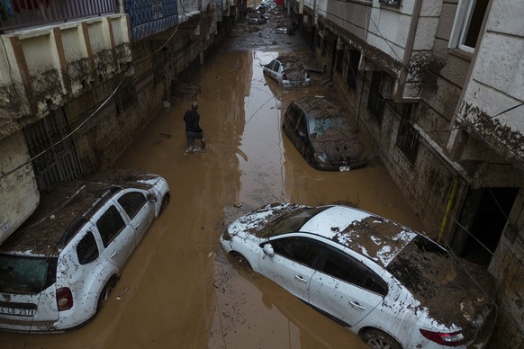 16.03.2023, Türkei, Sanliurfa: Ein Mann watet durch eine überschwemmte Straße, in der auch zahlreiche zerstörte Fahrzeuge stehen. Am Dienstag und Mittwoch hatte Starkregen nur fünf Wochen nach schwere ...