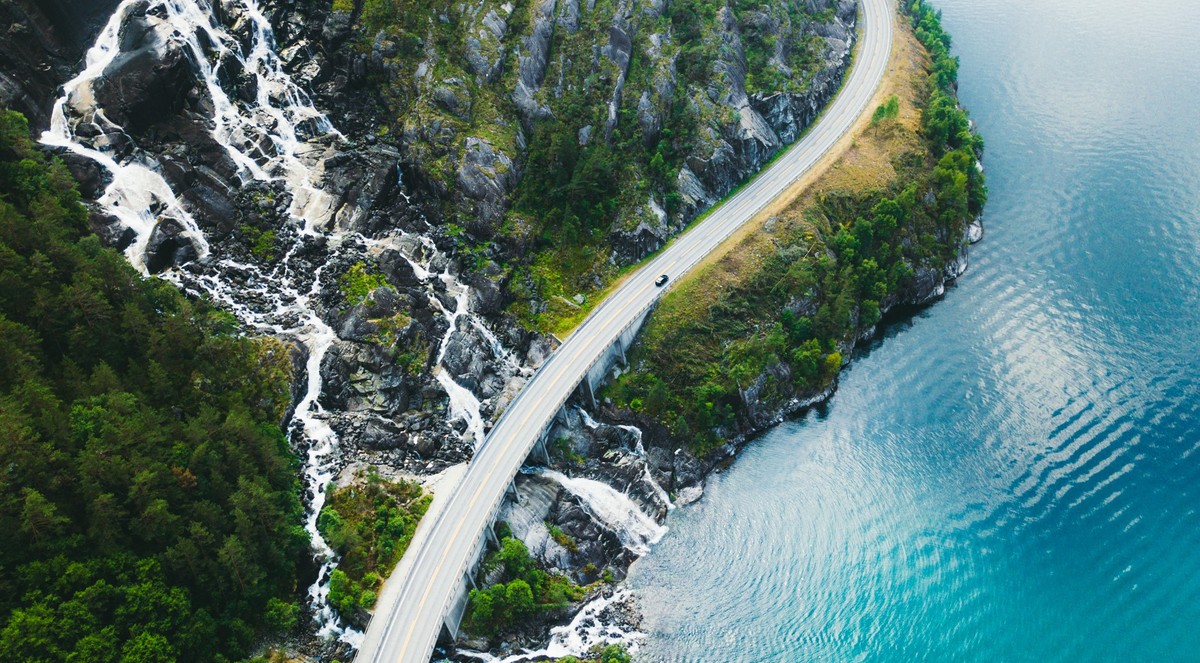 Drone panoramic photo of the car driving through picturesque road above the huge waterfall near the fjord in South Norway