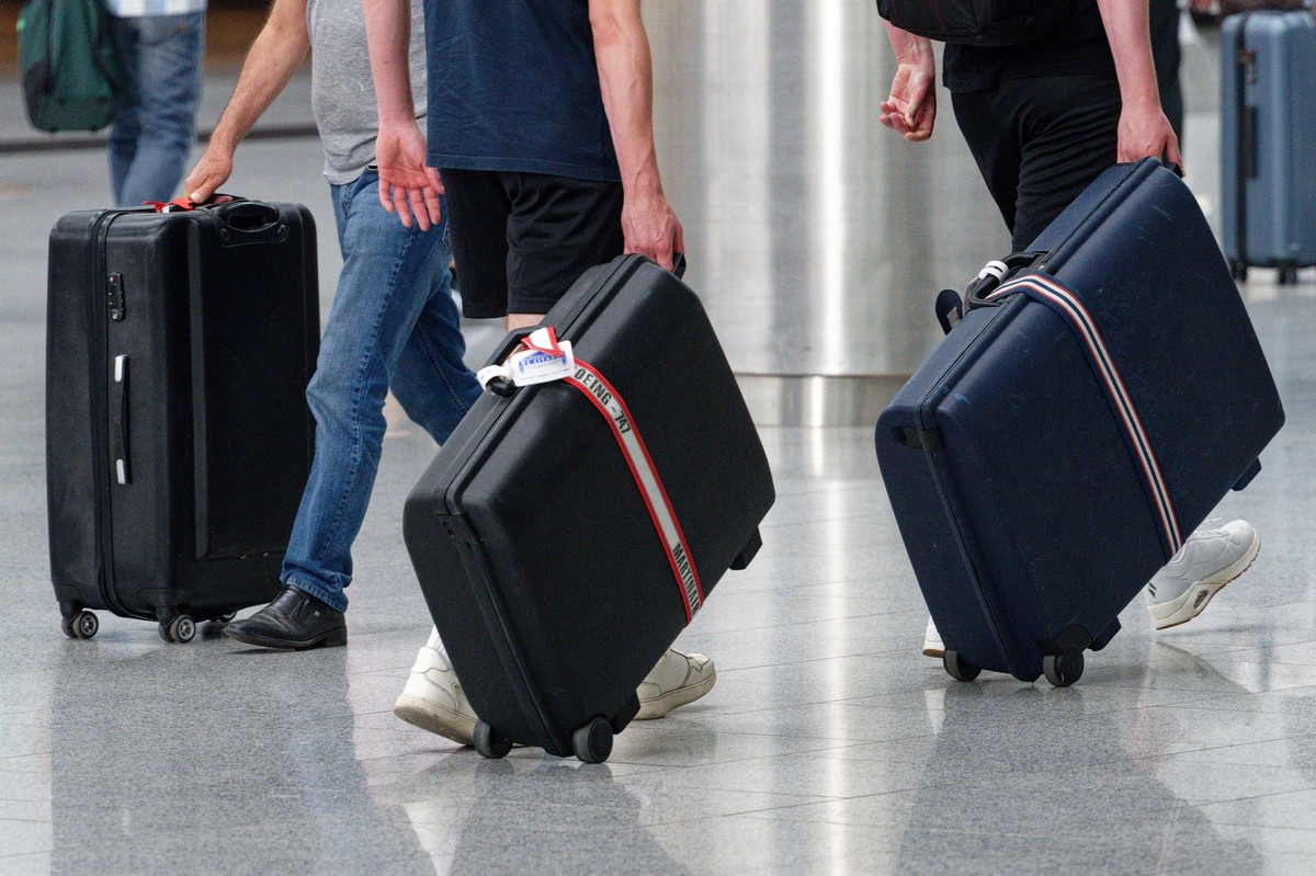 18.06.2023, Nordrhein-Westfalen, Düsseldorf: Reisende ziehen ihre Koffer zu einem Check-in-Schalter im Flughafen Düsseldorf. Foto: Henning Kaiser/dpa +++ dpa-Bildfunk +++