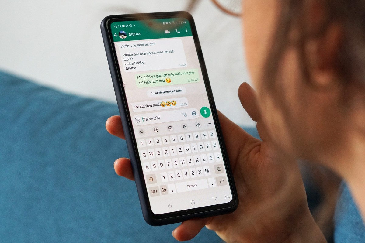 ILLUSTRATION - 29.09.2023, Berlin: Eine junge Frau hält ihr Smartphone in der Hand und liest eine Whatsapp-Nachricht von ihrer Mama. (zu dpa: «Der Smiley-Effekt: Wie Emojis empfundene Nähe steigern»)  ...