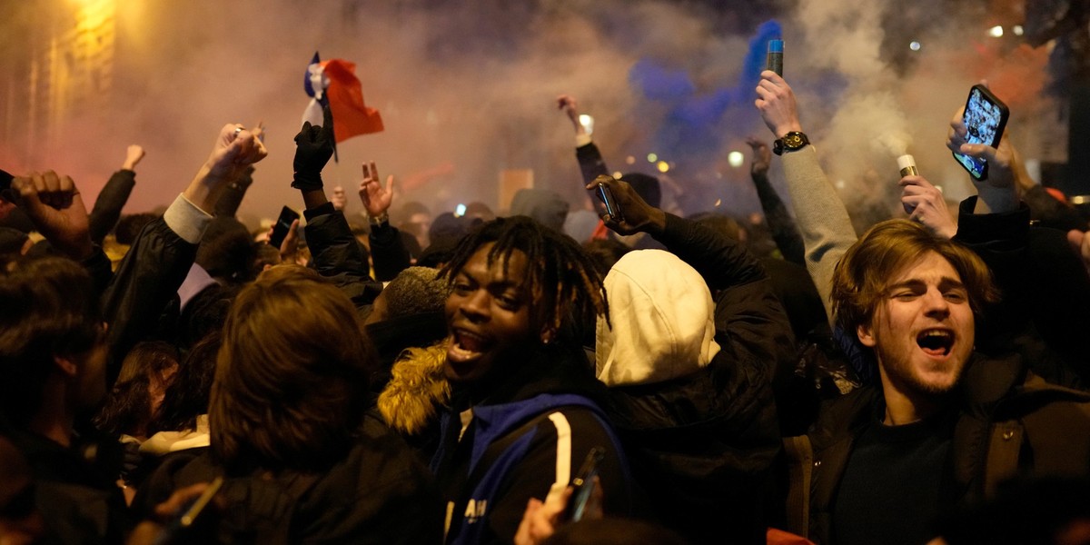14.12.2022, Frankreich, Paris: Fu�ball, WM, Frankreich - Marokko, Finalrunde, Halbfinale, Franz�sische Fans reagieren neben dem Arc de Triomphe auf der Avenue des Champs Elysees. Foto: Thibault Camus/ ...