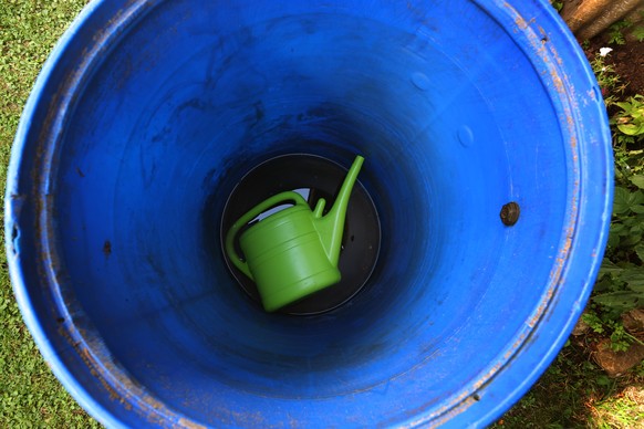 18.07.2022, Bayern, Kaufbeuren: Eine Gie�kanne liegt in einem Garten auf dem Boden einer fast leeren Regentonne. Foto: Karl-Josef Hildenbrand/dpa +++ dpa-Bildfunk +++