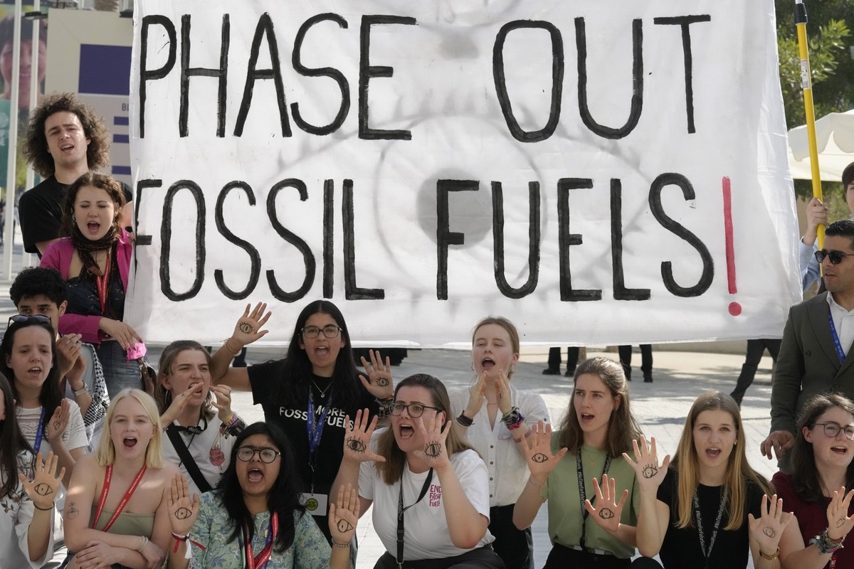 12.12.2023, Vereinigte Arabische Emirate, Dubai: Aktivisten demonstrieren mit einem Schild mit der Aufschrift "phase out fossil fuels" auf dem UN-Klimagipfel COP28. Foto: Peter Dejong/AP +++ ...