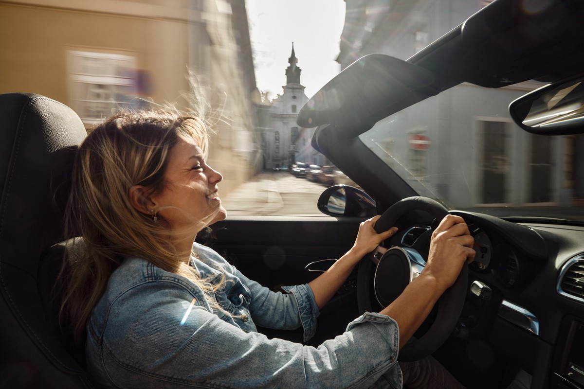 Happy woman enjoying while going on a trip by convertible car. Blurred motion.