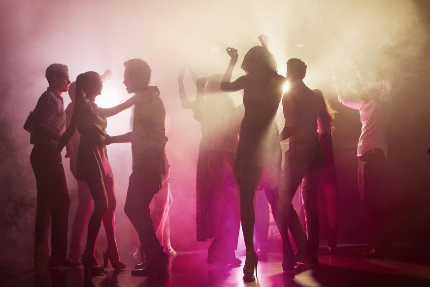 Group of people dancing on dance floor at nightclub