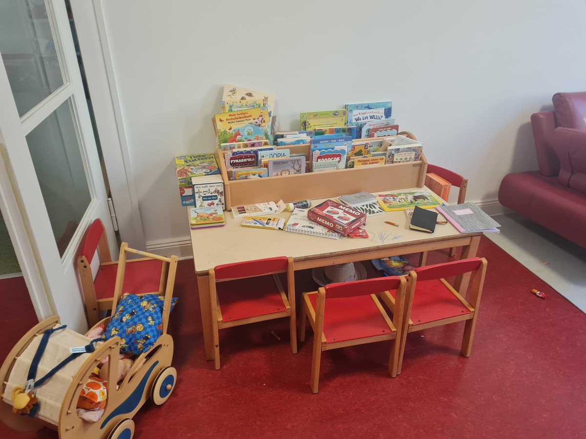 Ein Maltisch mit kleiner Kinderbibliothek in einem der Spielzimmer.