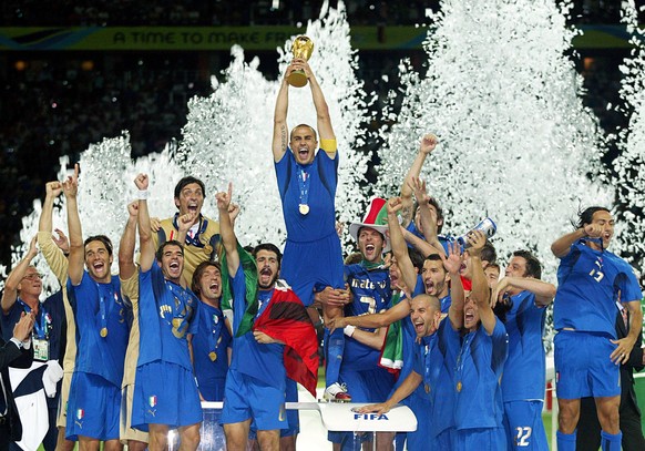 Der italienische Abwehrspieler und Kapitän Fabio Cannavaro (oben) reckt inmitten seiner jubelnden Teamgefährten im Konfetti-Regen triumphierend den eroberten WM-Pokal in die Höhe. Italiens FußballNati ...