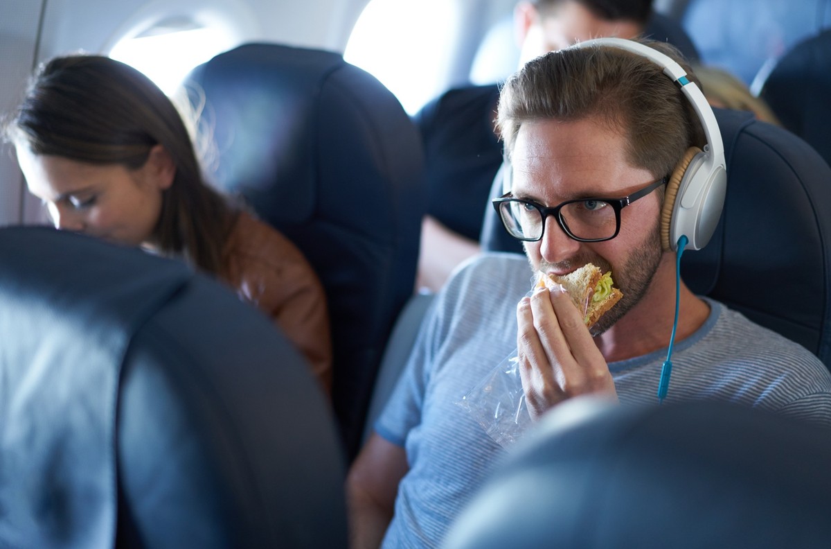 Man eating sandwich in economy class in airplane