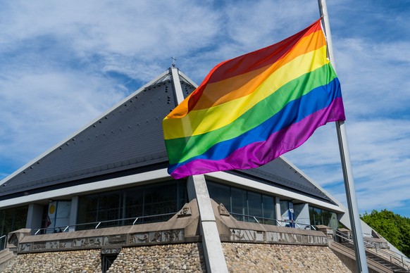 Eine Regenbogenfahne weht vor der Autobahnkirche St. Christophorus