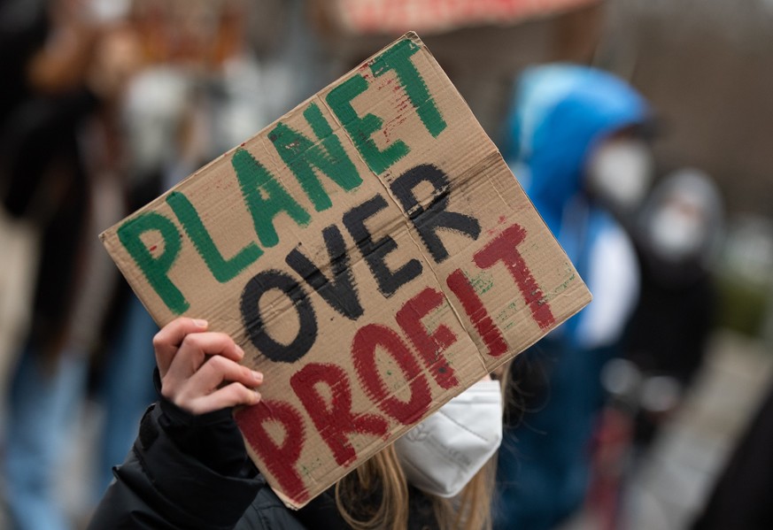 ARCHIV - 17.12.2021, Berlin: Bei einer Demonstration der Klimaaktivisten Fridays For Future trägt eine Teilnehmerin ein Plakat mit der Aufschrift &quot;Planet over Profit&quot;. In keinem einzigen der ...