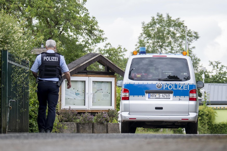 Ein Polizist steht am Eingang der Kleingartenanlage in Münster, in der Ende April vier Männer zwei Jungen missbraucht haben sollen.