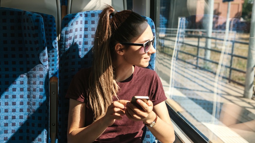 A young girl rides a train and uses a mobile phone. Train ride.