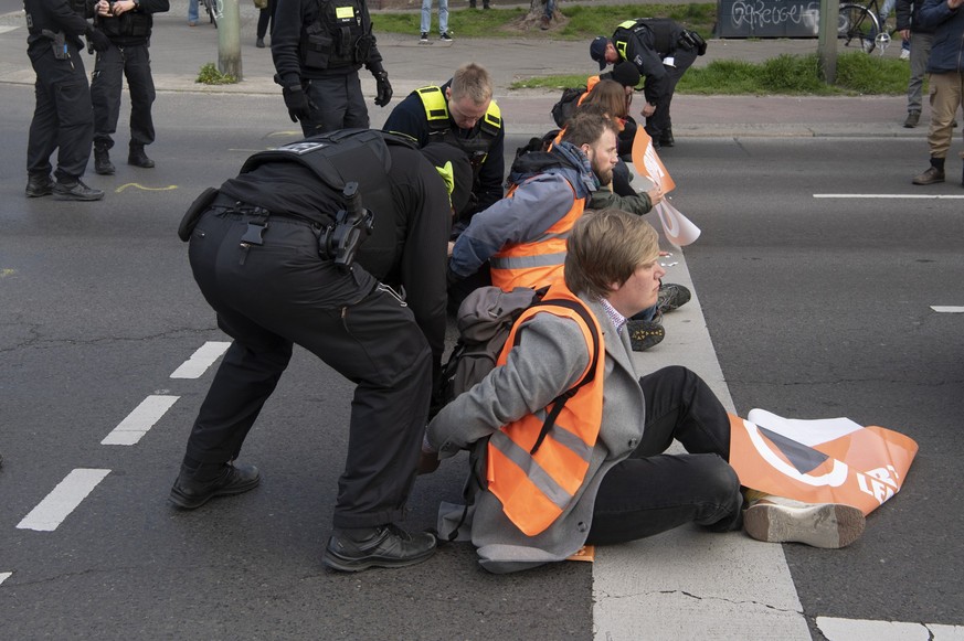 27.04.2023, Berlin: Aktivisten der Gruppierung Letzte Generation blockieren eine Kreuzung an der Landsberger Allee. Polizisten sind im Einsatz, um die Blockade aufzulösen. Foto: Paul Zinken/dpa +++ dp ...