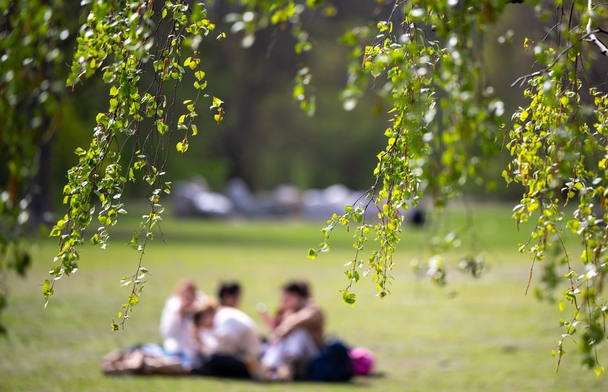 05.04.2024, Berlin: Junge Menschen sitzen beim sonnigen Wetter auf dem Rasen im Tiergarten. (zu dpa: