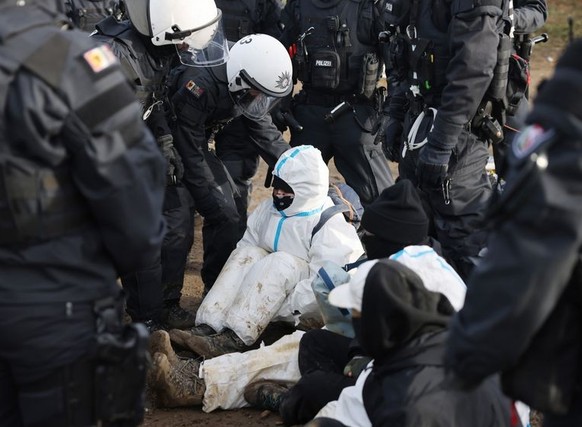 10.01.2023, Nordrhein-Westfalen, Erkelenz: Polizeibeamte entfernen einen Klimaschutzaktivisten aus einer Straßenblockade am Rand der Ortschaft Lützerath. Lützerath soll zur Erweiterung des Braunkohlet ...