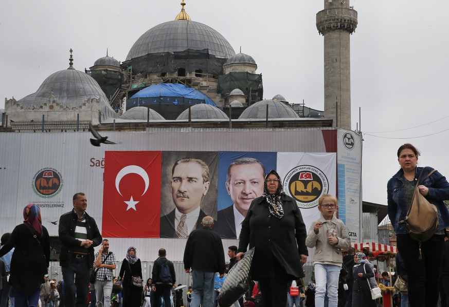 Backdropped by posters of Mustafa Kemal Ataturk, centre left, founder of modern Turkey, and current President Recep Tayyip Erdogan, centre right, hang from a restoration wall on the Yeni Cami (New Mos ...