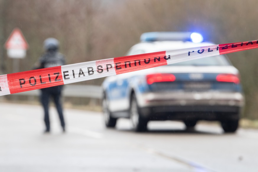 31.01.2022, Rheinland-Pfalz, Mayweilerhof: Polizeibeamte stehen an einer Absperrung an der Kreisstra�e 22, rund einen Kilometer von dem Tatort entfernt, an dem zwei Polizeibeamte durch Sch�sse get�tet ...