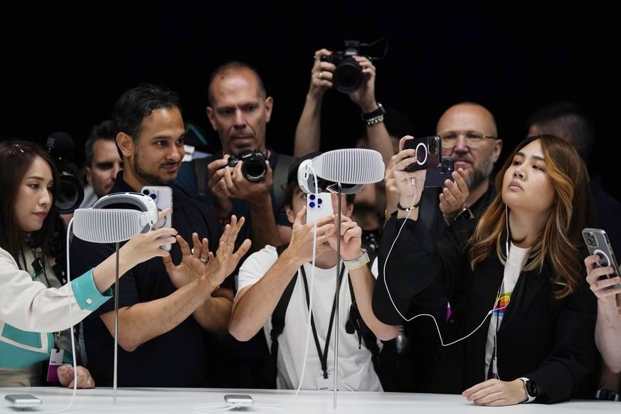 A crowd gathers around the Apple Vision Pro headset as it is displayed in a showroom on the Apple campus Monday, June 5, 2023, in Cupertino, Calif. (AP Photo/Jeff Chiu)