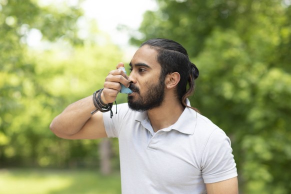 Young man in nature using asthma inhaler model released Symbolfoto PUBLICATIONxINxGERxSUIxAUTxHUNxONLY SGF02376