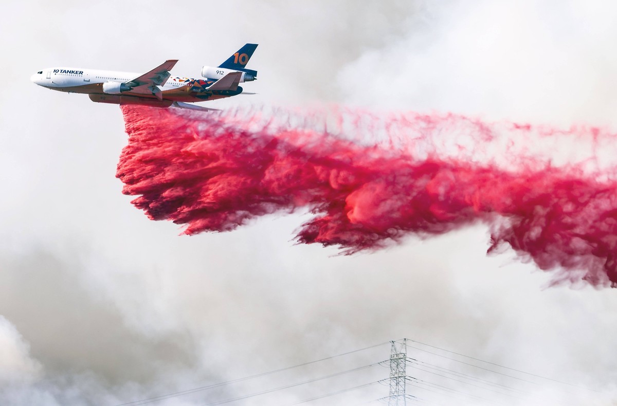January 11, 2025, Los Angeles, California, USA: A plane drops Phos-Chek fire retardant into Mandeville Canyon, one of the neighborhoods threatened by the Palisades Fire, which spread north and east ov ...