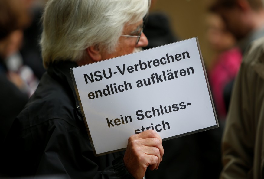 A person holds a placard reading "finally solve NSU crimes - dont mark it finished" in front of a Munich court before judges give their verdict in the trial of suspected NSU neo-Nazi gang me ...