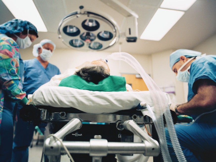 Surgeon and nurses standing next to bed