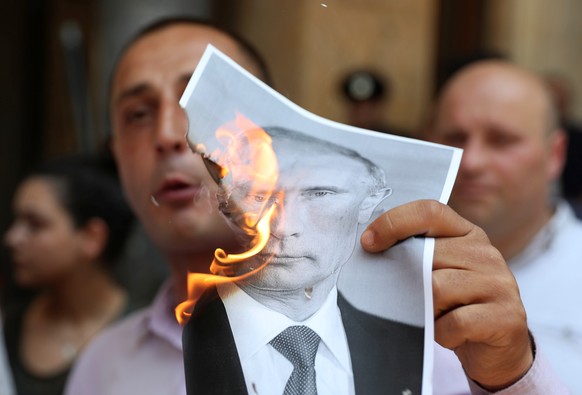 A participant burns a portrait of Russia&#039;s President Vladimir Putin during a rally to protest against the visit of the Russian delegation in Tbilisi, Georgia June 20, 2019. REUTERS/Irakli Gedenid ...