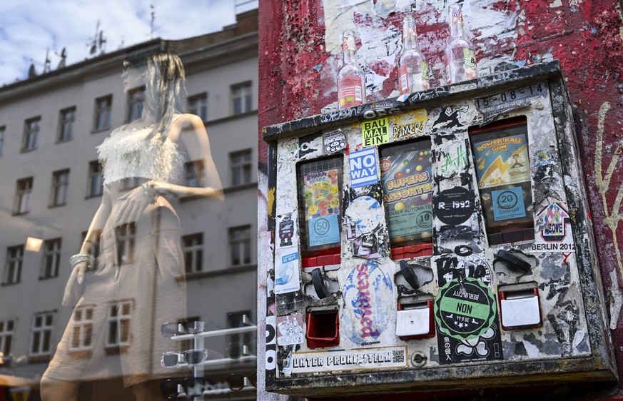 PRODUKTION - 15.07.2023, Berlin: Ein Kaugummiautomat hängt an einer Häuserfassade neben einem Ladengeschäft in der Oranienstraße in Kreuzberg und wird auch zum Abstellen von leeren Flaschen benutzt. O ...