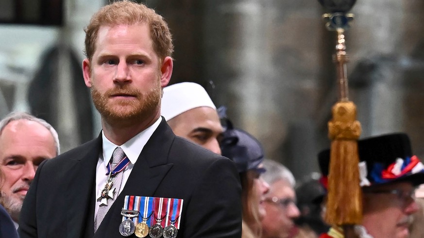 ARCHIV – 6. Mai 2023, Großbritannien, London: Der britische Prinz Harry, Herzog von Sussex, sieht zu, wie sein Vater, der britische König Charles III.  Nach seiner Krönung steht die Westminster Abbey im Zentrum...