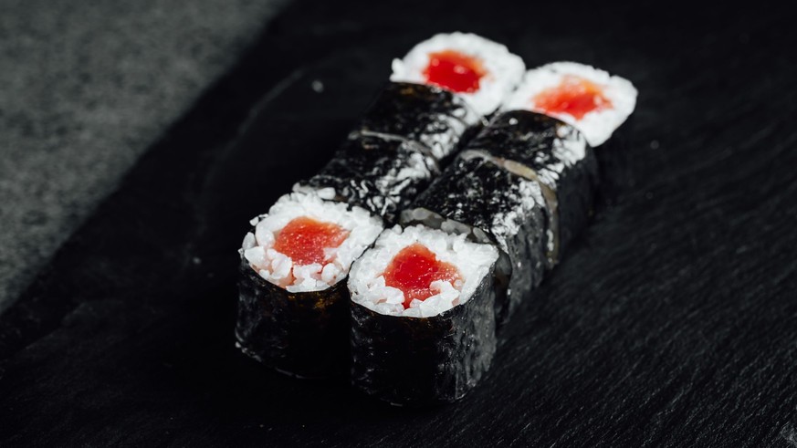 RECORD DATE NOT STATED A closeup of a set of fresh delicious Tekka Maki rolls on a black plate *** einer closeupe des einer setzen des Frisch K