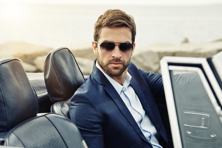 Serious man suited in sports car, portrait