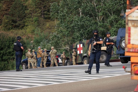 People work as Kosovo police and U.S. and EU troops stand by after one police officer was killed, another hurt in Kosovo gunfire, in Josevik, Kosovo September 24, 2023. REUTERS/Fatos Bytyci