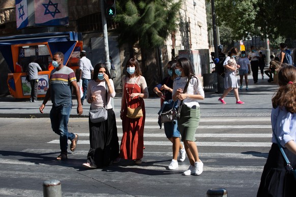 Jerusalem, Israel - July 12, 2020: People wearing protective masks cross the road around CBS.