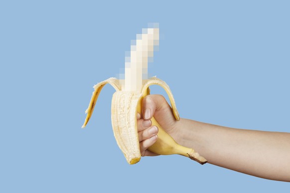 Hidden censored banana in hand on a blue background. Horny (aroused) penis, male erection and sexual education. Funny pornography.