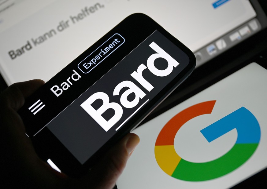 ILLUSTRATION - 13.07.2023, Hessen, Frankfurt/Main: Vor zwei Google-Logos ist das Wort &quot;Bard&quot; auf dem Display eines Smartphones zu sehen. Das KI-Chatbot Bard von Google ist jetzt auch in Deut ...