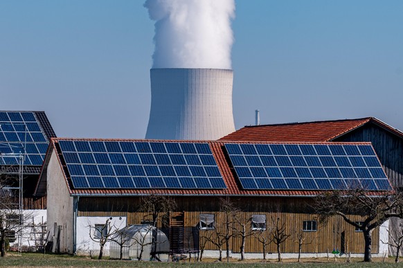 Wasserdampf steigt aus dem Kühlturm vom Atomkraftwerk (AKW) Isar 2. Davor steht ein Stall mit einer Photovoltaikanlage Das Kernkraftwerk im Landkreis Landshut ist das letzte in Bayern, das noch nicht  ...